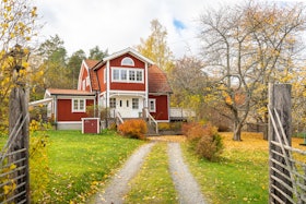 Old traditional red wooden house in Sweden. Countryside in autumn day.View of beautiful European garden design. Golden, yellow, brown, red colors of leaves Old traditional red wooden house in Sweden. Countryside in autumn day.View of beautiful European garden design. Golden, yellow, brown, red colors of leaves