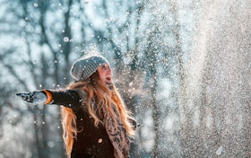 Smiling woman throwing snow in the air at sunny winter day Smiling woman throwing snow in the air at sunny winter day